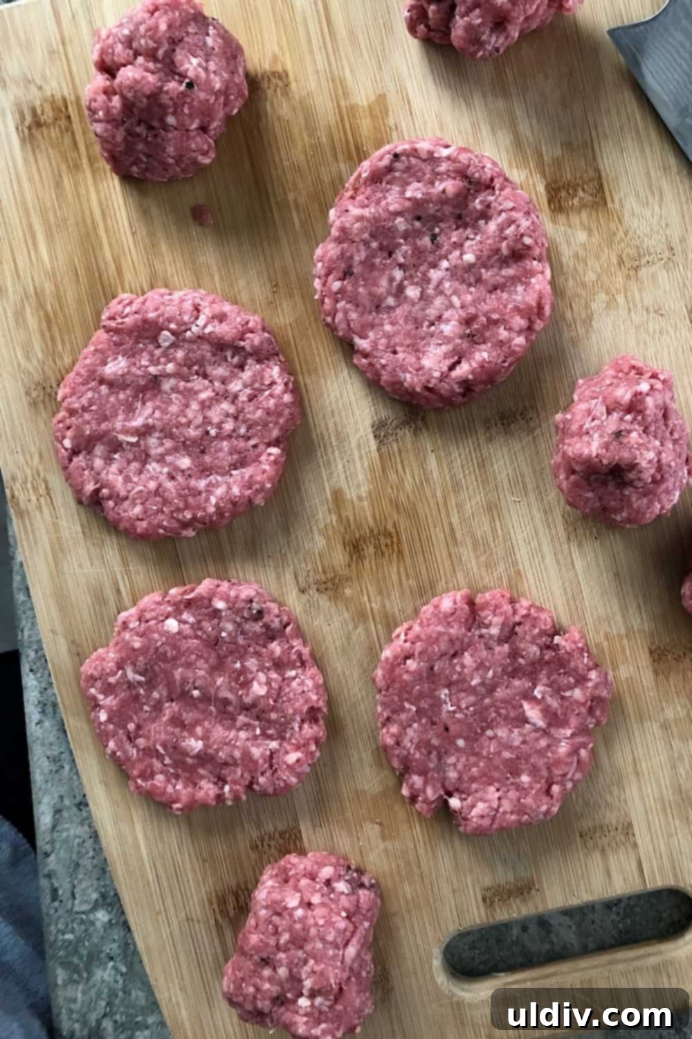 Copycat Big Mac Sliders 4 Uncooked mini burger patties made from ground beef, seasoned and ready for cooking on a cutting board.