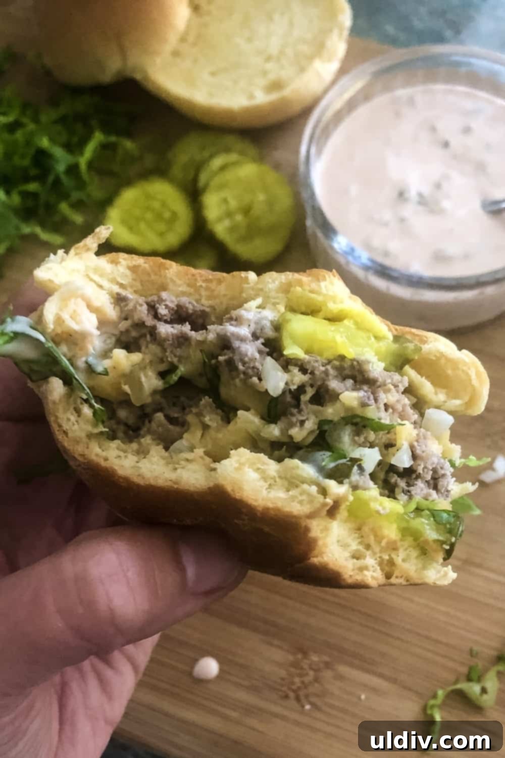 Copycat Big Mac Sliders 5 A Big Mac slider with two bites taken out, showcasing the layers of meat, cheese, sauce, and toppings.