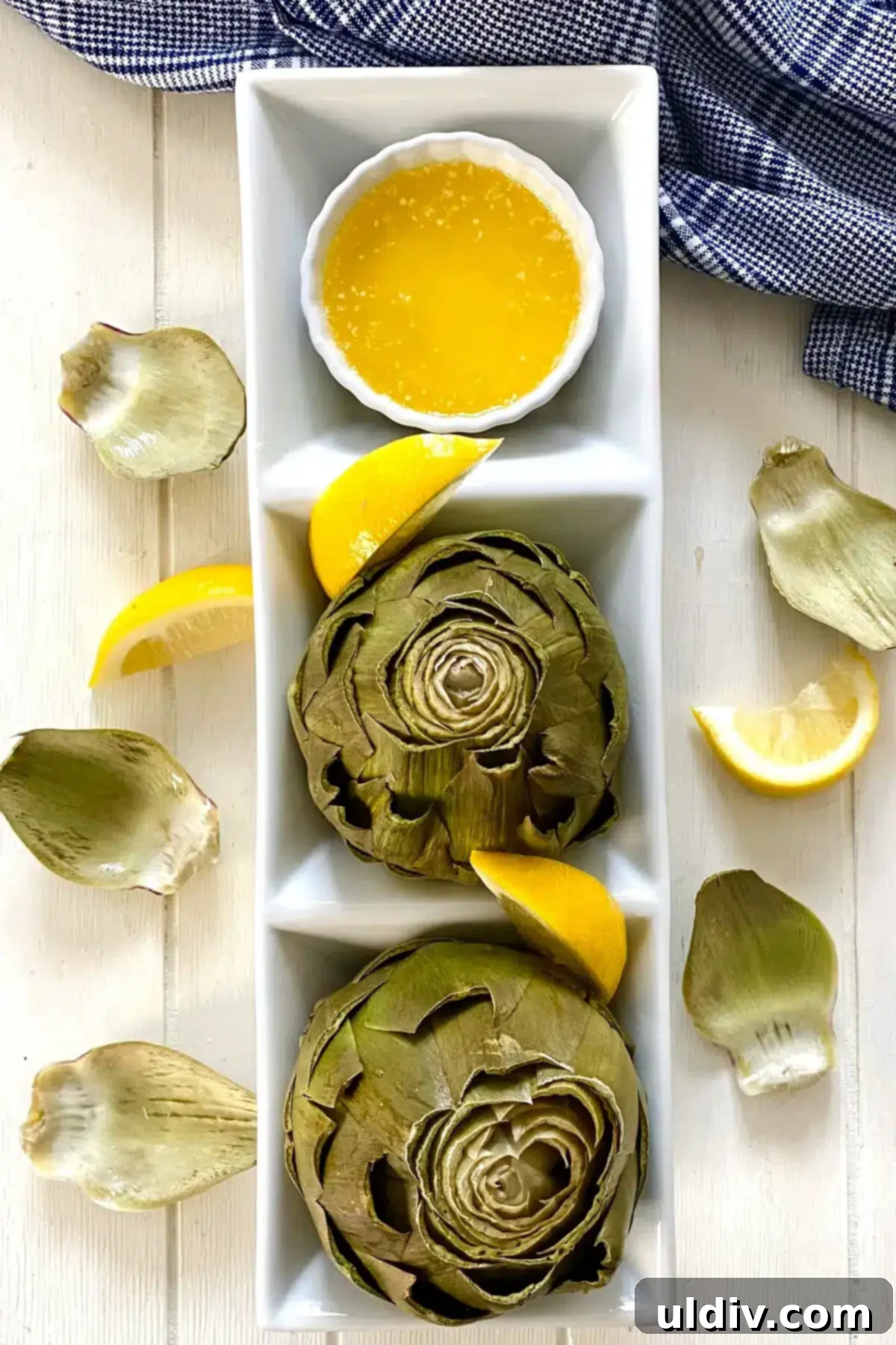 Microwave Magic: Artichokes in Minutes 11 Two cooked microwave artichokes presented elegantly with melted butter and lemon wedges.