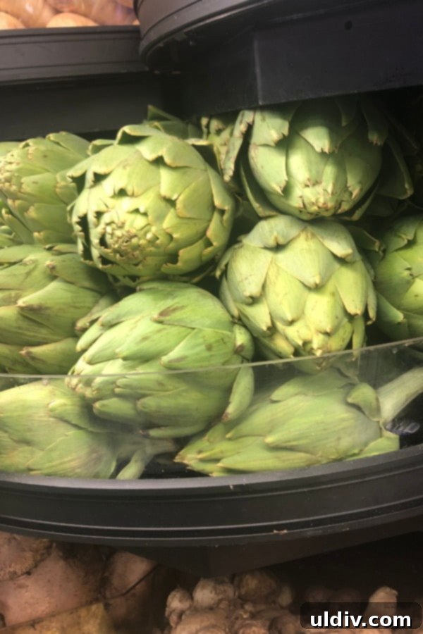 Quick & Easy Microwave Artichokes 15 A full bin of fresh artichokes at a grocery store, inviting shoppers to pick their perfect produce.