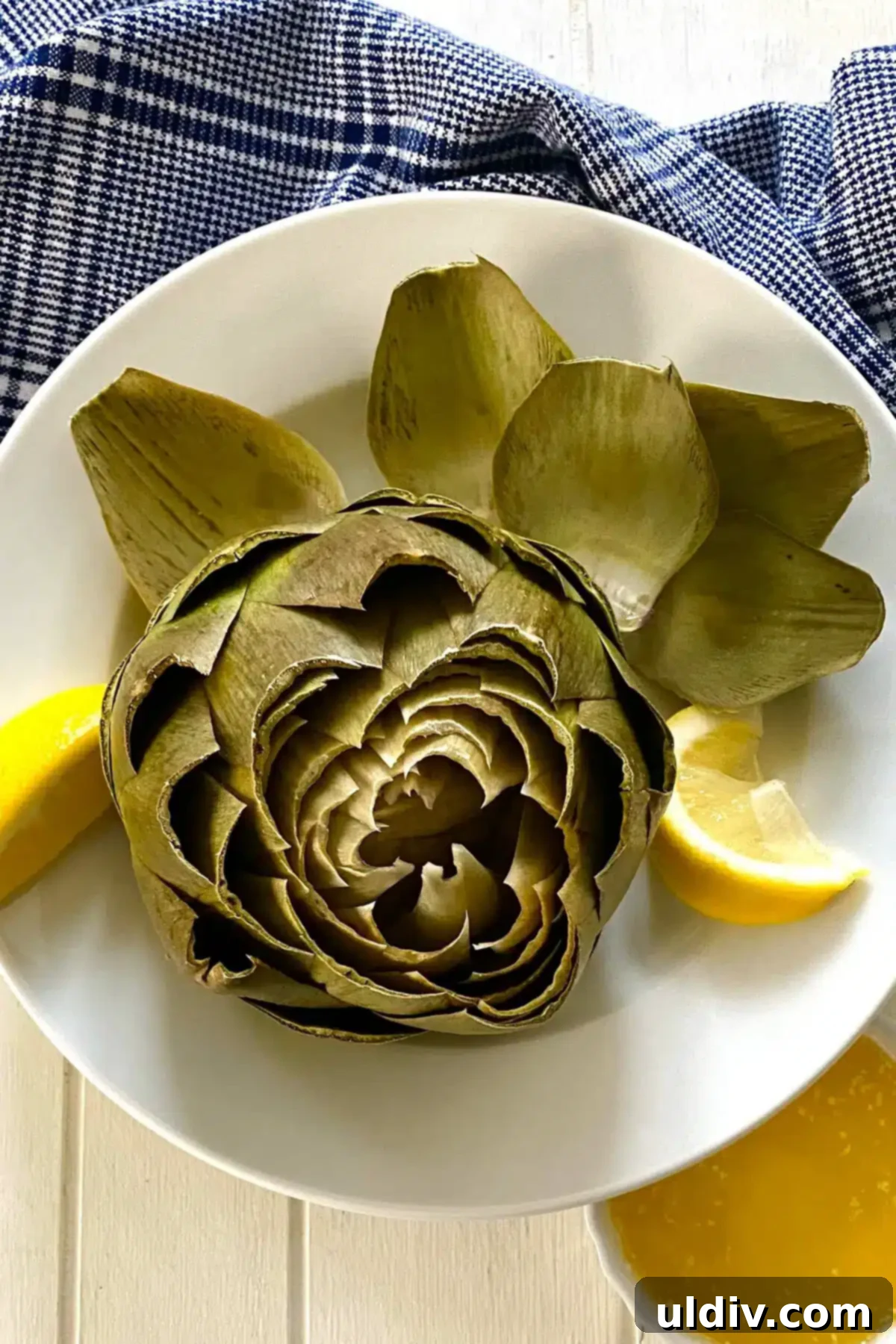 Microwave Magic: Artichokes in Minutes 3 A cooked artichoke with some outer leaves removed, revealing the tender interior, served with lemon.