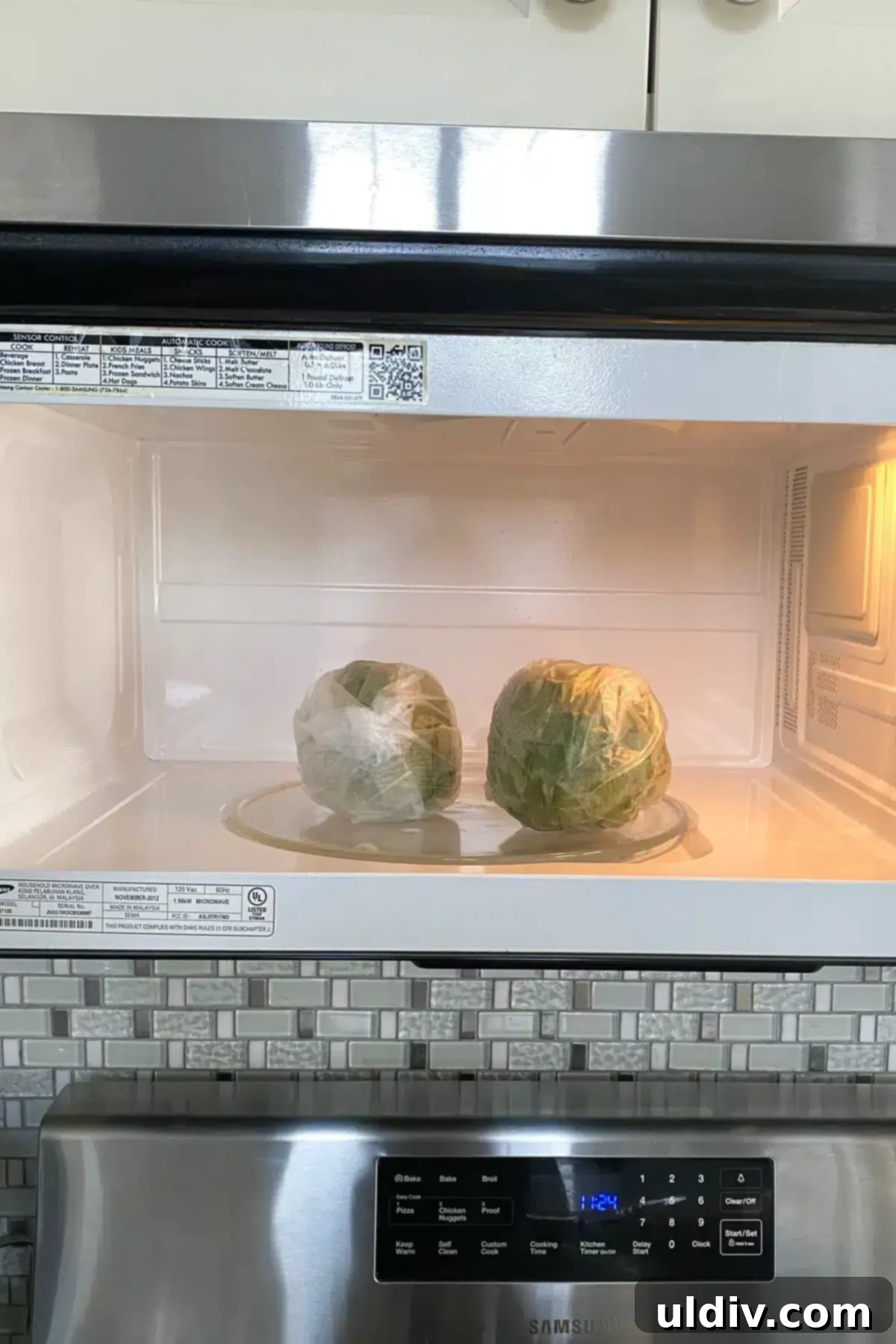Quick & Easy Microwave Artichokes 8 Two plastic-wrapped artichokes placed inside a microwave, ready to be cooked.
