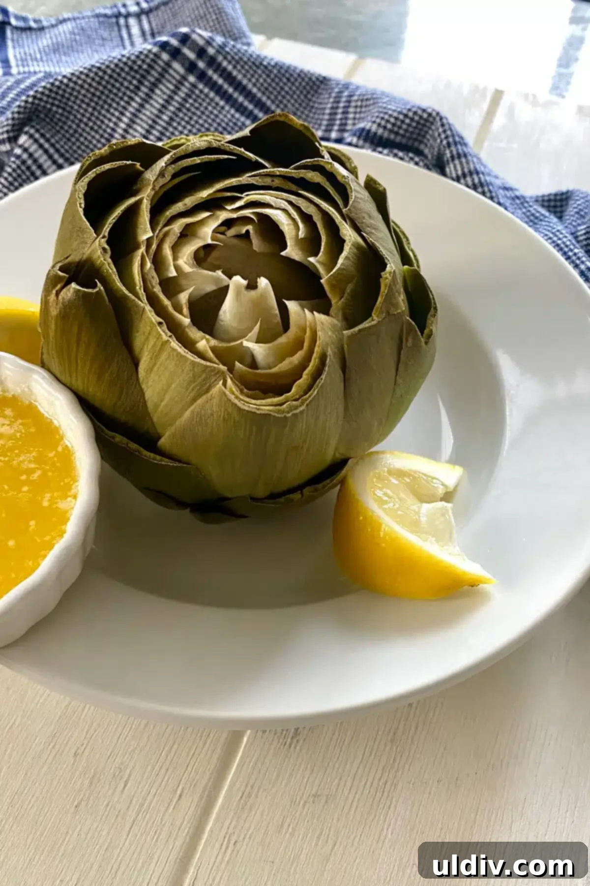 Quick & Easy Microwave Artichokes 10 A perfectly cooked artichoke, ready to eat, served with a small bowl of melted butter.
