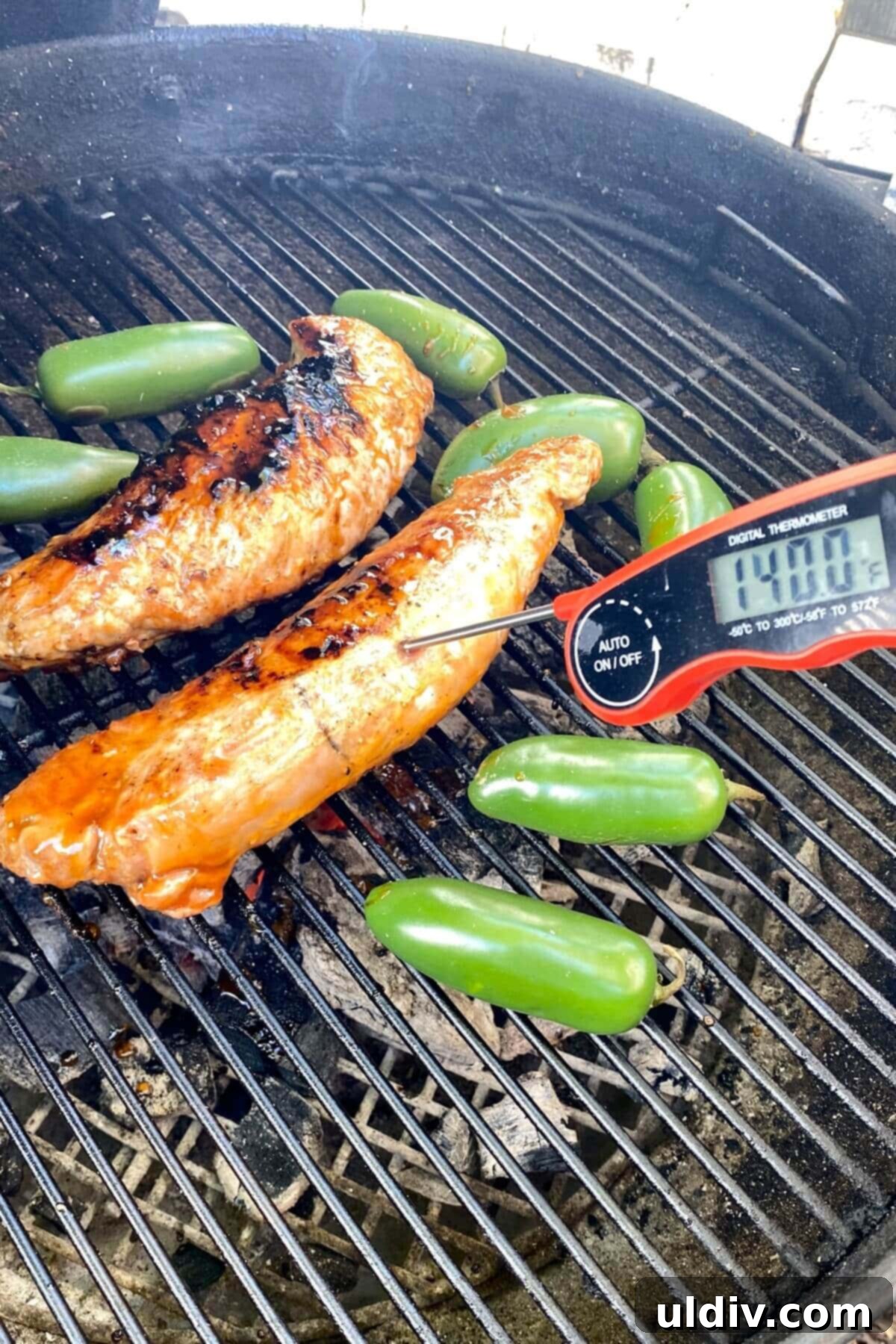 Sweet Heat Pork Tenderloin 11 pork tenderloin on a grill with a digital thermometer at 140 degrees F.