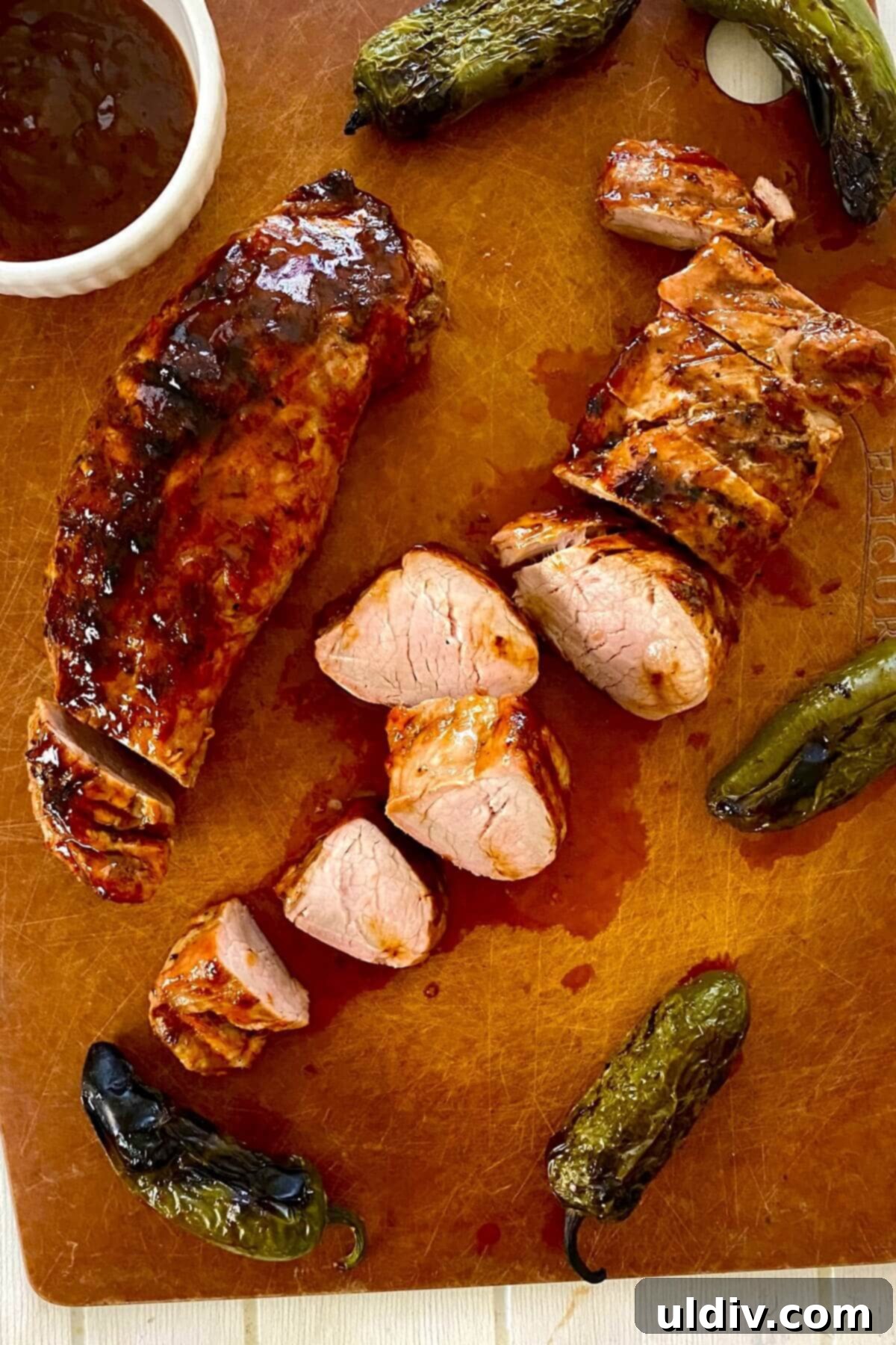 Sweet Heat Pork Tenderloin 10 sliced glazed pork tenderloin on a cutting board.