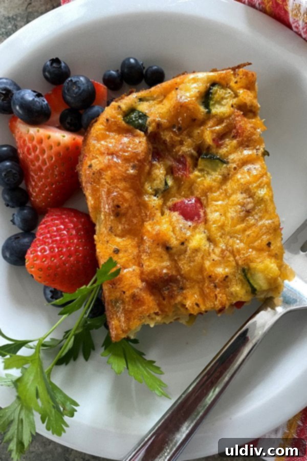 Hearty Cheesy Sausage and Spinach Breakfast Bake 7 A colorful breakfast casserole slice featuring fluffy eggs, diced ham, red pepper, zucchini, and melted cheddar cheese, demonstrating the recipe's versatility.