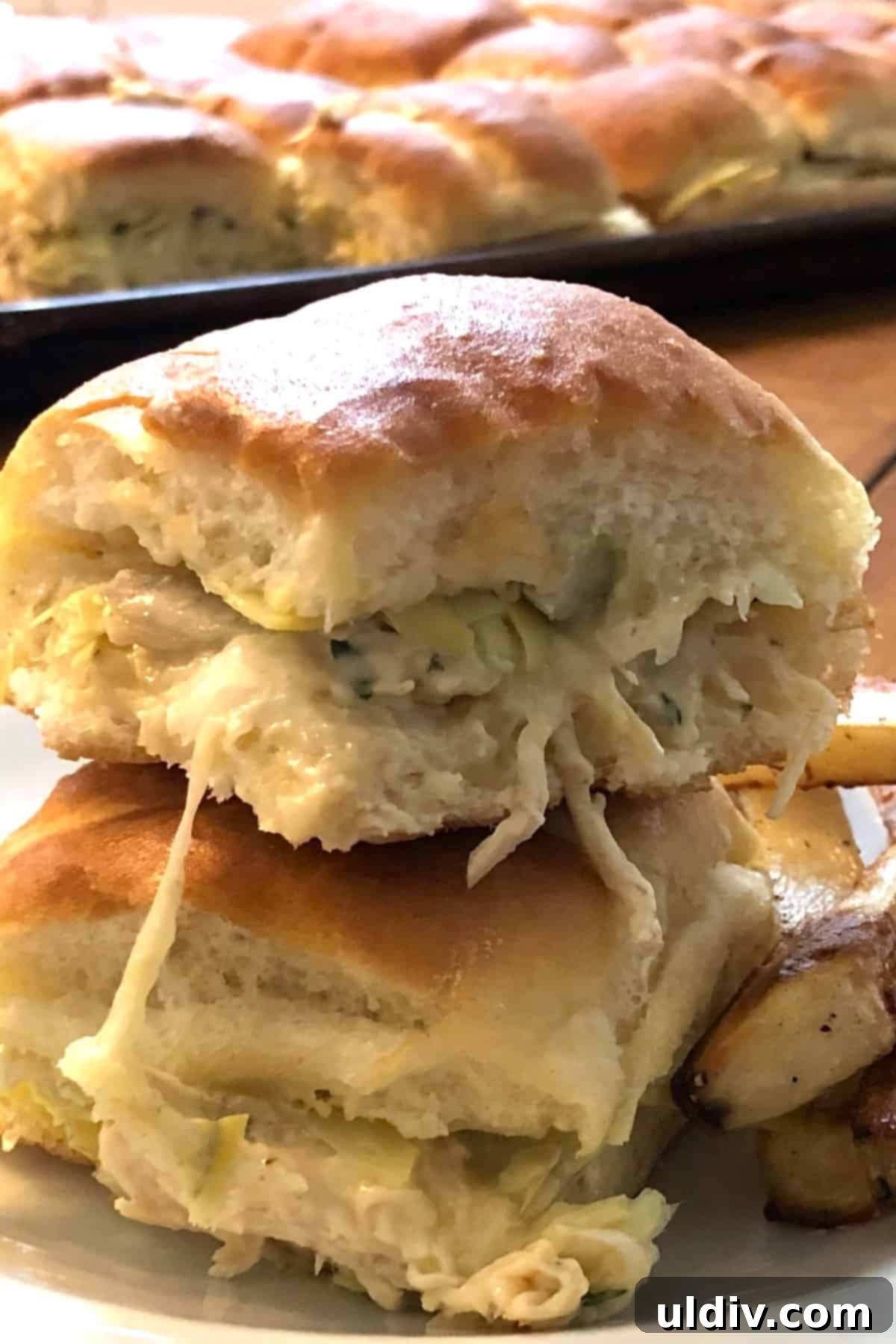 Melty Turkey Sliders with Dreamy Artichoke Dip 2 Two turkey sliders stacked on top of each other with golden French fries.