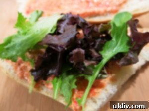 Mediterranean Sunshine Panino: Manchego & Jamón Serrano 4 Salad leaves laid over roast red pepper dip on the bottom half of a sandwich bun