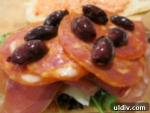 Mediterranean Sunshine Panino: Manchego & Jamón Serrano 9 Black olives and the top bun, spread with dip, completing the panino assembly