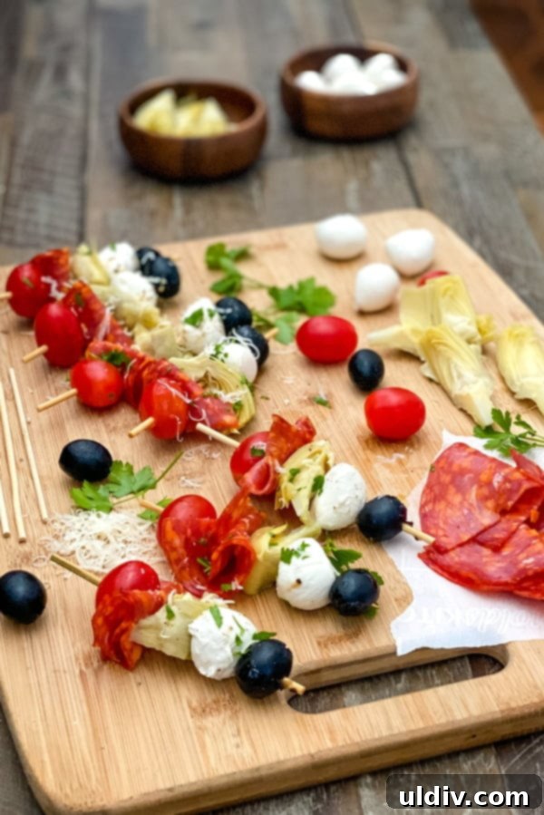 No-Fuss Antipasto Picks 6 Delicious appetizer on kebab sticks with fresh tomatoes, mozzarella, and artichoke hearts arranged on a wooden board.