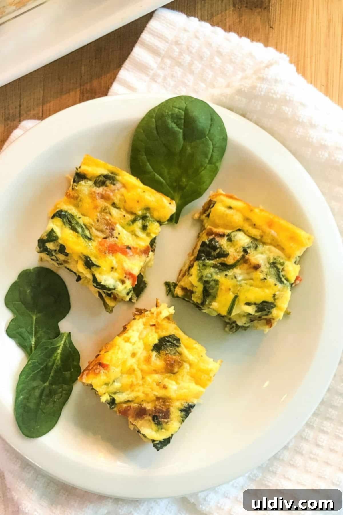 Crustless Spinach and Bacon Quiche Bites 2 Three golden-brown crustless spinach and bacon quiche squares on a plate, ready to be enjoyed.