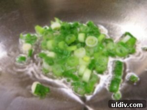 Cinco de Mayo Weekend Double Stacked Tortilla Sandwich Feast 3 Chopped green onions sizzling in a pan with vegetable oil, turning translucent.