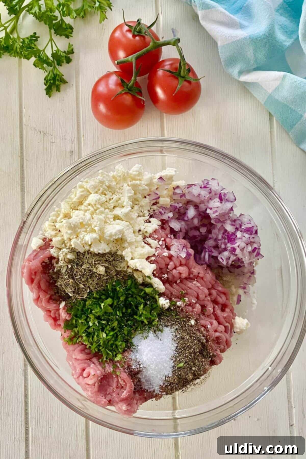 A bowl showcasing ground turkey, fresh parsley, crumbled feta, and chopped onions, perfectly prepped for making Greek turkey burgers.