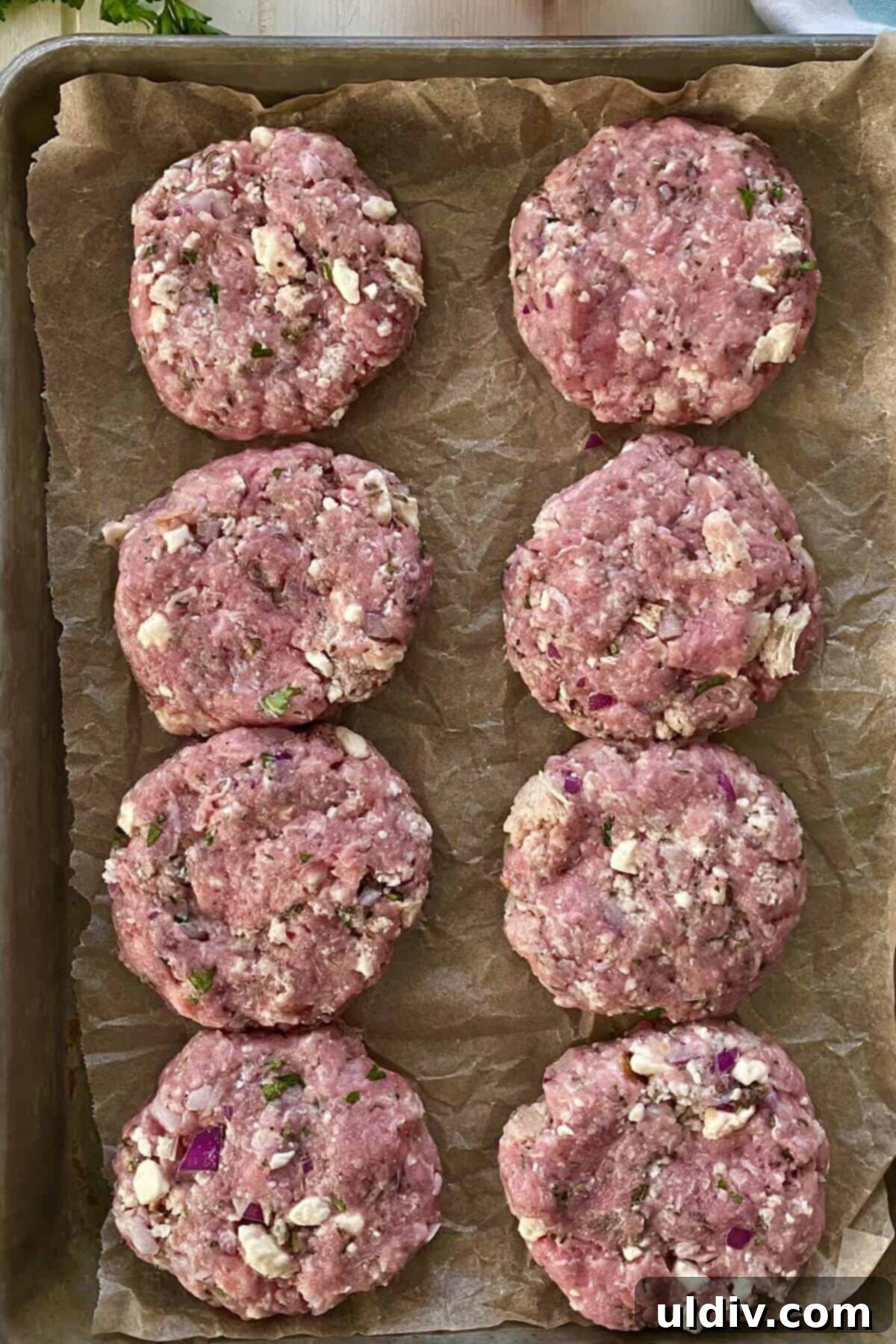 Neatly formed uncooked mini Greek turkey burgers, ready for grilling or pan-frying.