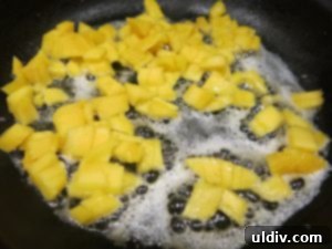 Sweetest Mom, Sweetest Treat: Decadent Mango Crepes for Mother's Day 13 Cooking chopped mango in melted butter in a pan