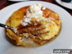 Stack of fluffy lemon ricotta pancakes with maple syrup and whipped butter