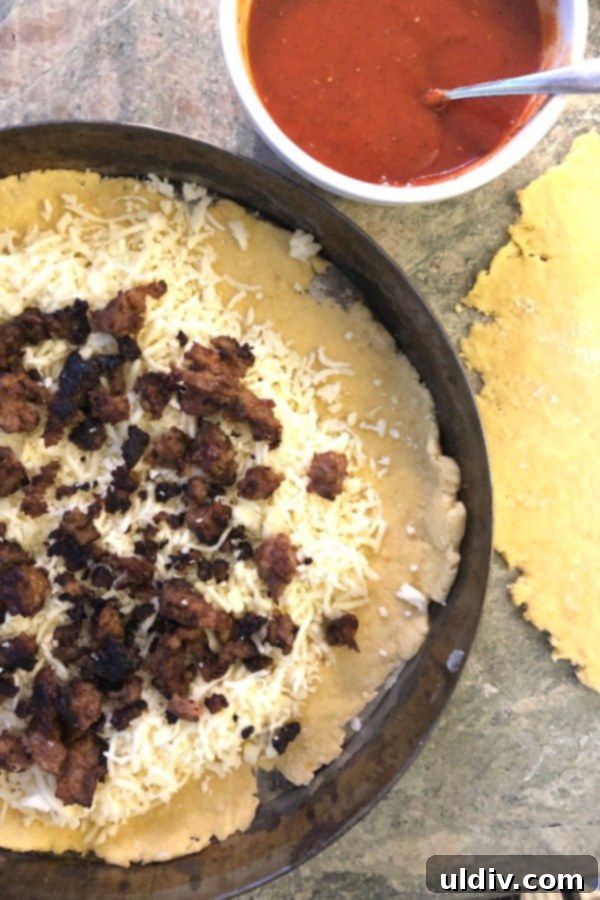 Mastering Authentic Stuffed Pizza 3 Detailed shot of preparing a stuffed pizza, layering tomato sauce, Italian sausage, and mozzarella cheese.