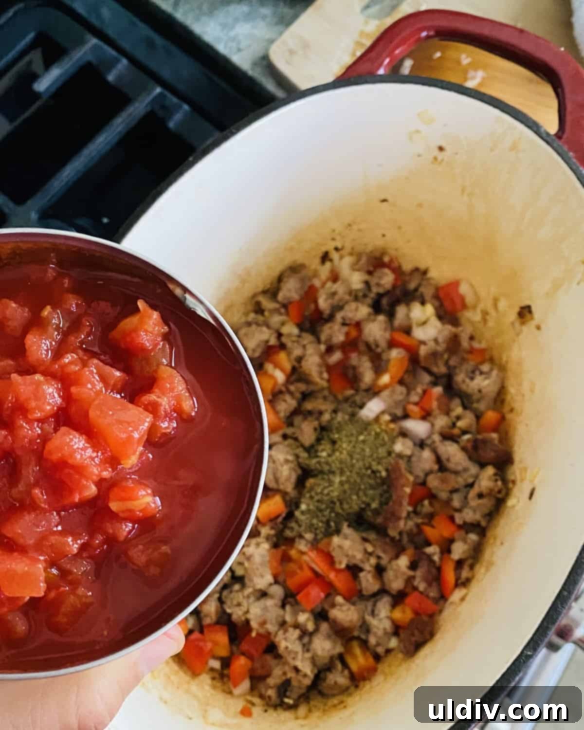 Adding canned diced tomatoes and tomato sauce to cooked Italian sausage and vegetables.