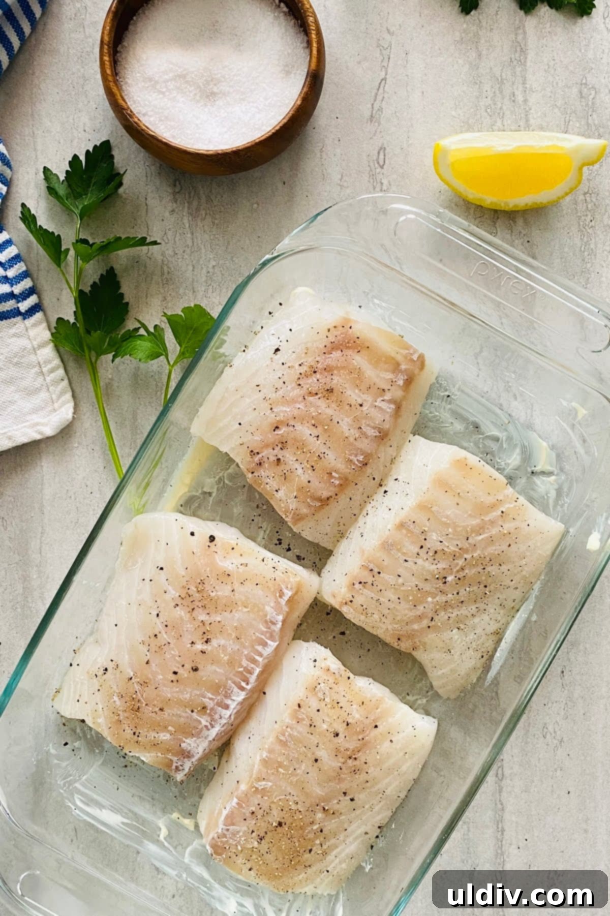 Golden-Crisp Garlic Herb Panko Baked Cod 7 Four fresh cod fillets arranged in a buttered baking dish, lightly seasoned with salt and pepper.