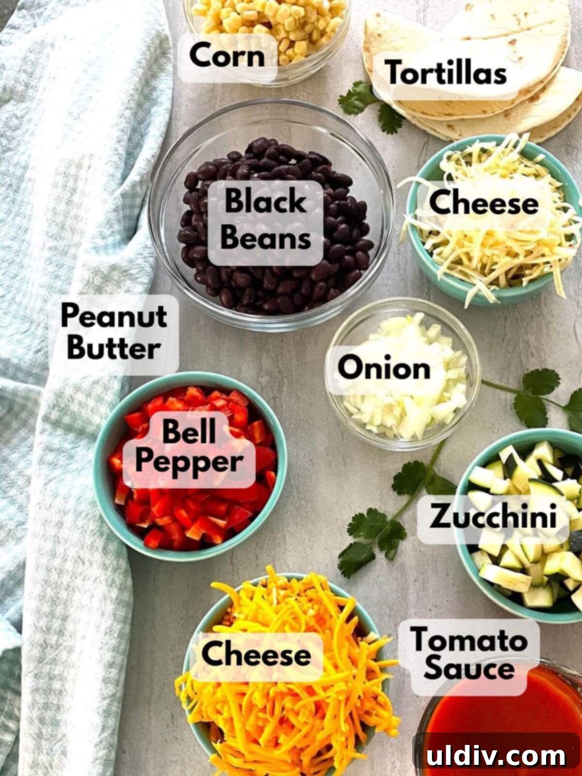 Effortless Healthy Black Bean Enchiladas 3 A vibrant flat lay of black beans, shredded cheese, sliced red peppers, diced onions, and soft tortillas, ready for enchilada preparation.