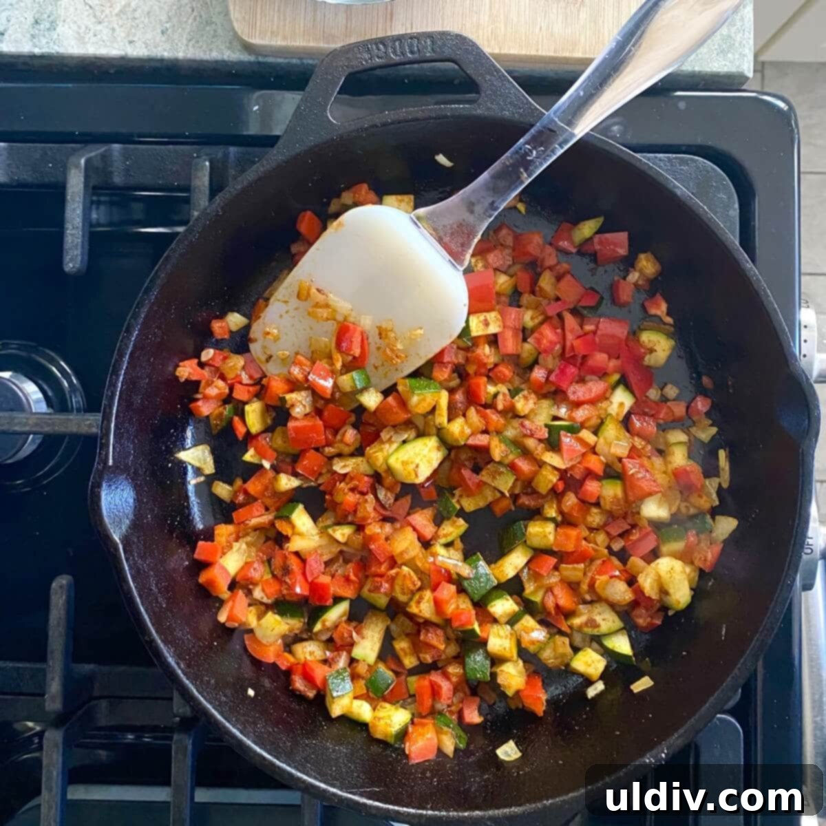 Simple Wholesome Black Bean Enchiladas 5 A cast iron skillet filled with colorful, freshly sautéed vegetables, including onions, red peppers, and zucchini, perfectly softened and slightly caramelized.