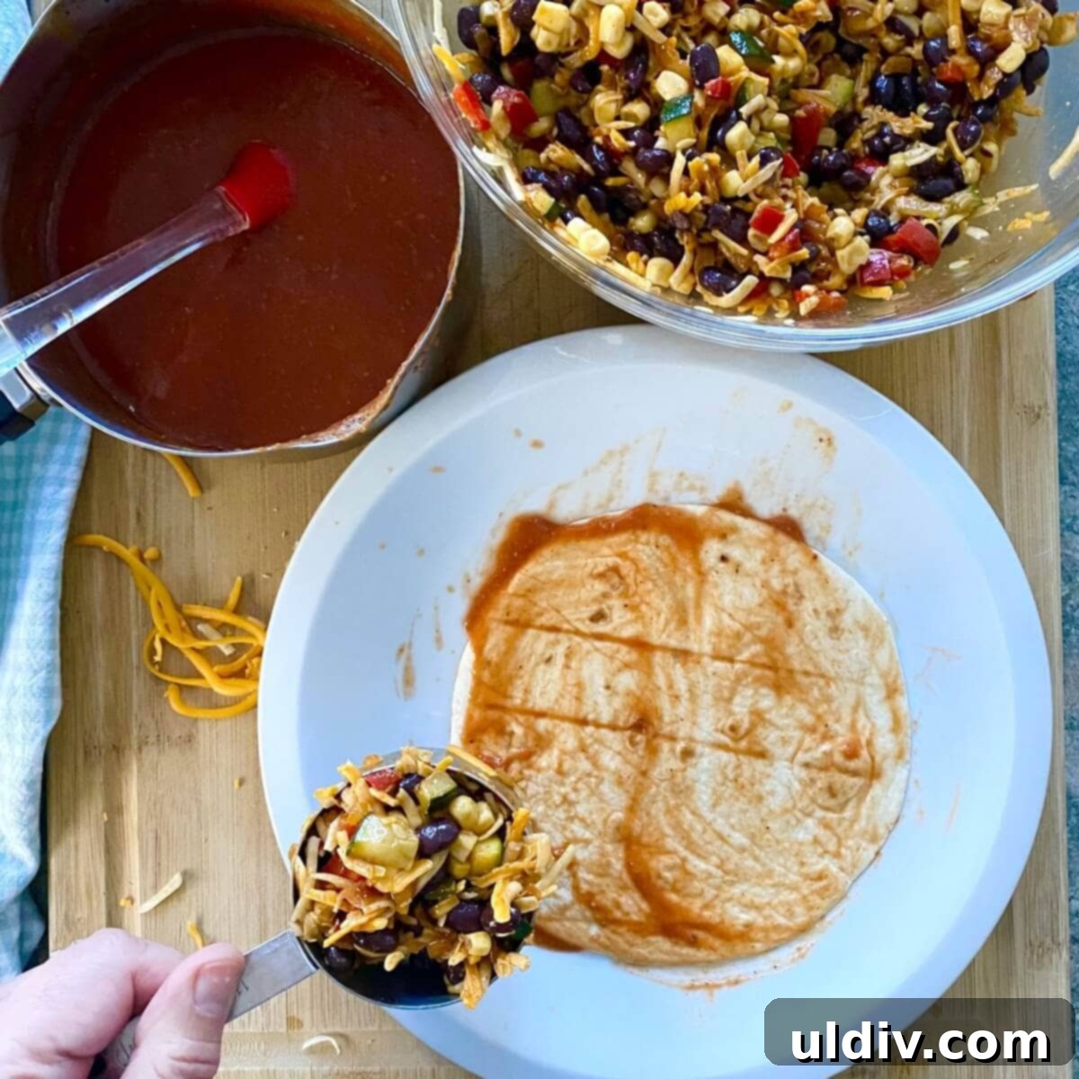Effortless Healthy Black Bean Enchiladas 7 A single flour tortilla being filled with a generous scoop of the black bean and vegetable mixture, ready for rolling.