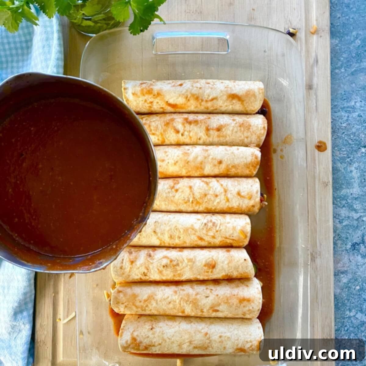 Effortless Healthy Black Bean Enchiladas 8 Unbaked enchiladas neatly arranged in a baking dish, generously topped with the vibrant red enchilada sauce, awaiting the final layer of cheese.