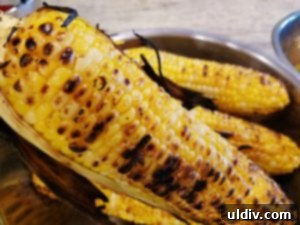 Grilled Veggie Panino Still My First Flame 5 A child's hand holding a piece of grilled corn, ready to eat