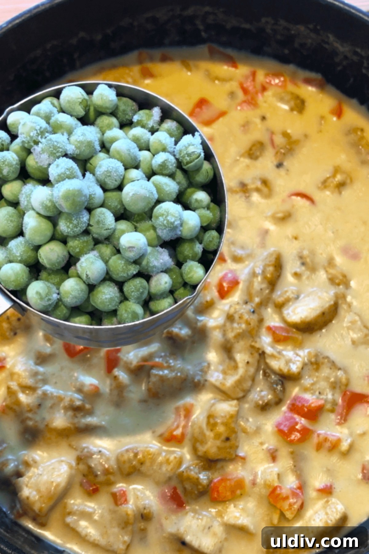 Creamy Thai Coconut Chicken Curry 7 Green peas being added to the simmering Thai chicken curry in a sauté pan.