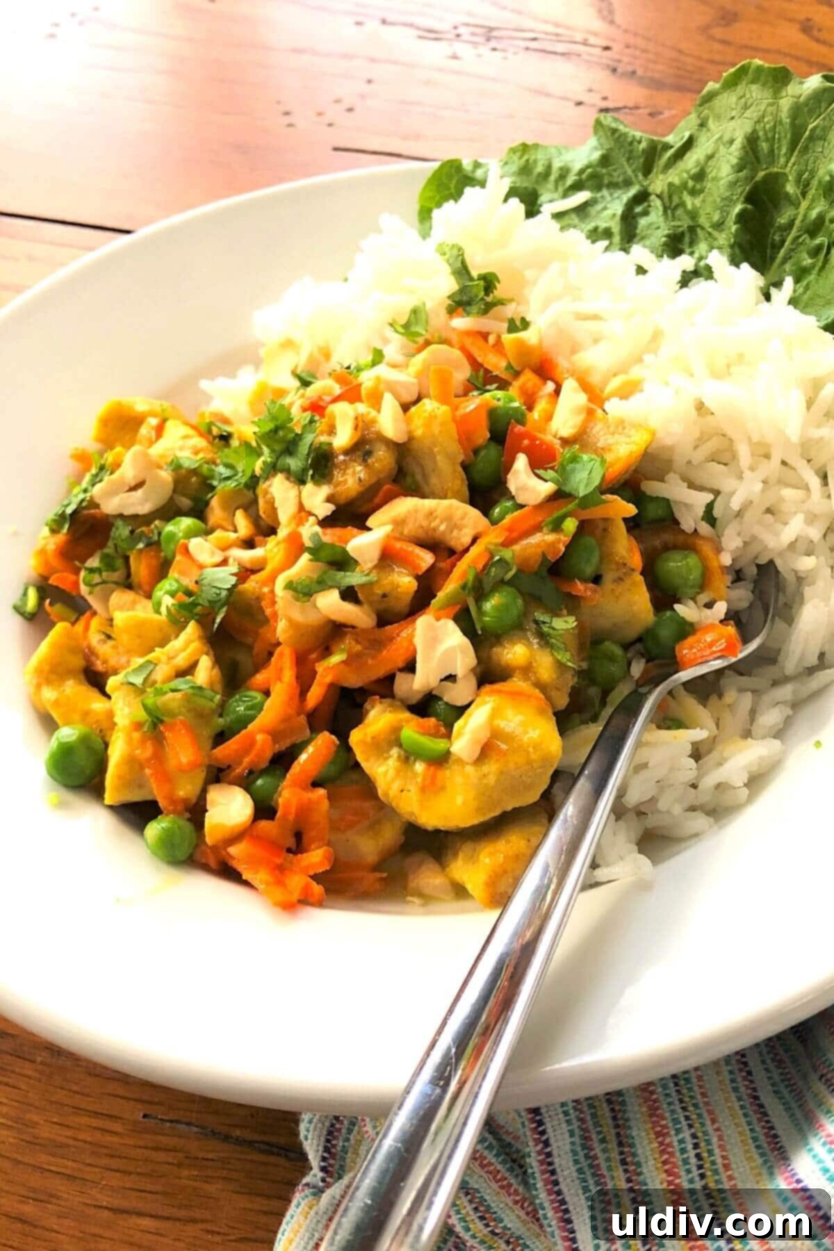 Creamy Thai Coconut Chicken Curry 8 A serving of Thai chicken curry over jasmine rice in a bowl, garnished with cilantro and cashews.