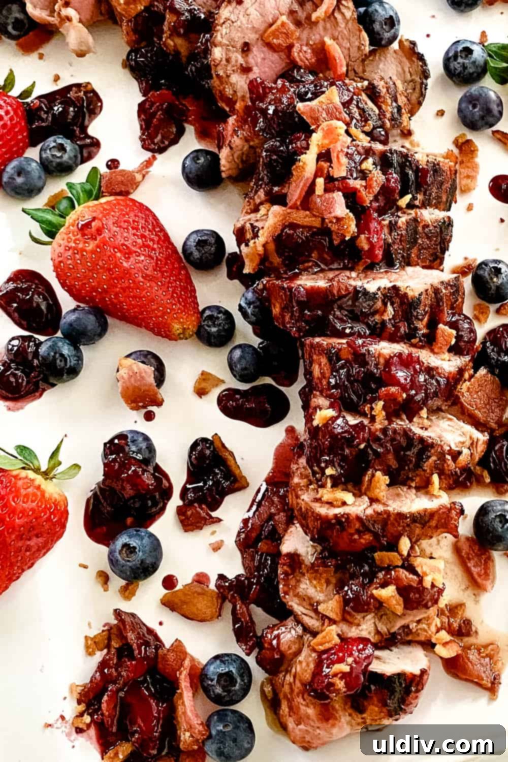 Berry Bacon Glazed Grilled Pork Tenderloin 5 Expertly sliced grilled pork tenderloin fanned out on a platter, generously coated with the vibrant berry bacon sauce.