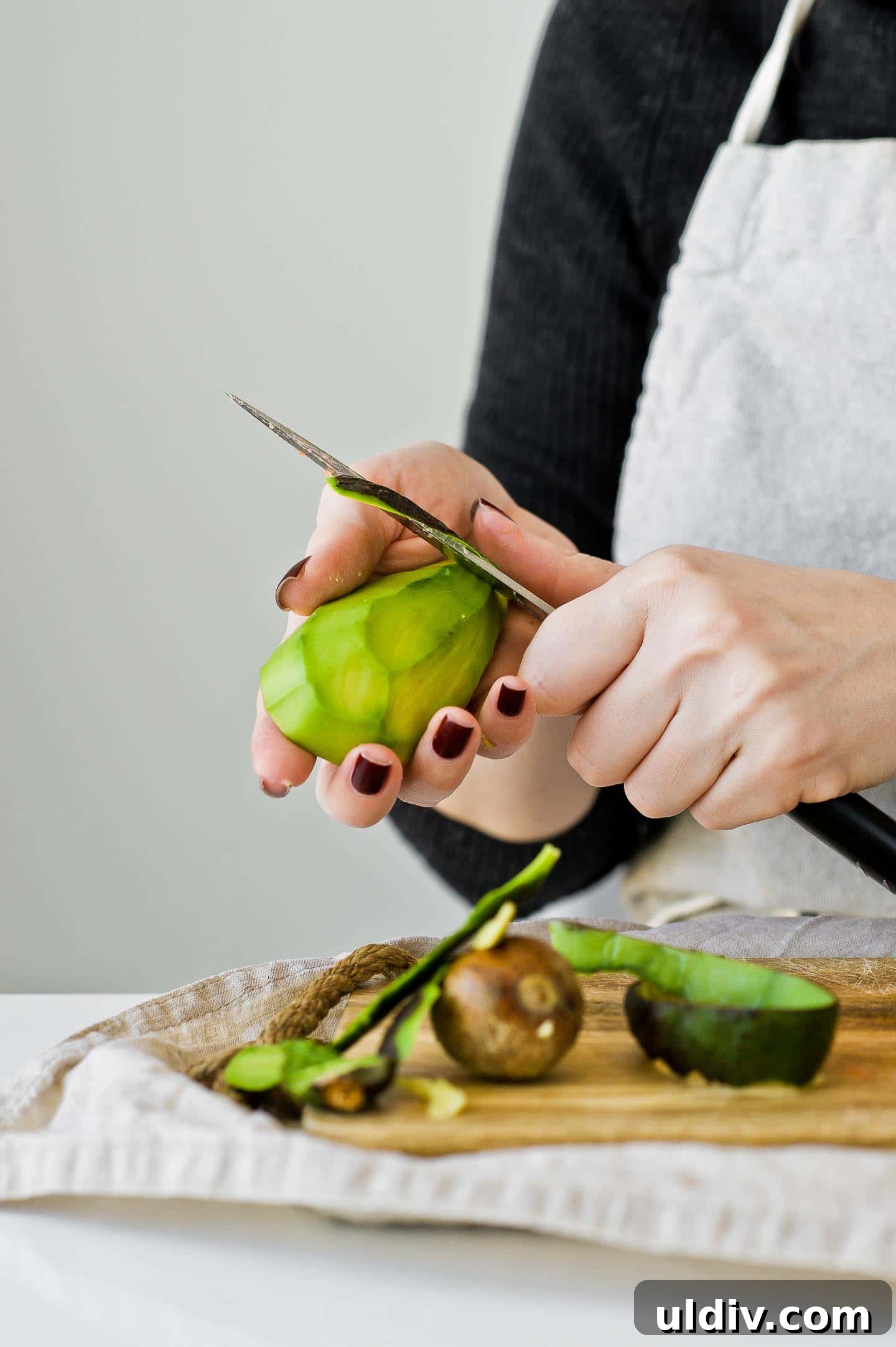 Refreshing Green Smoothie Recipes for Energy and Detox 3 Woman is peeling an avocado with a knife.