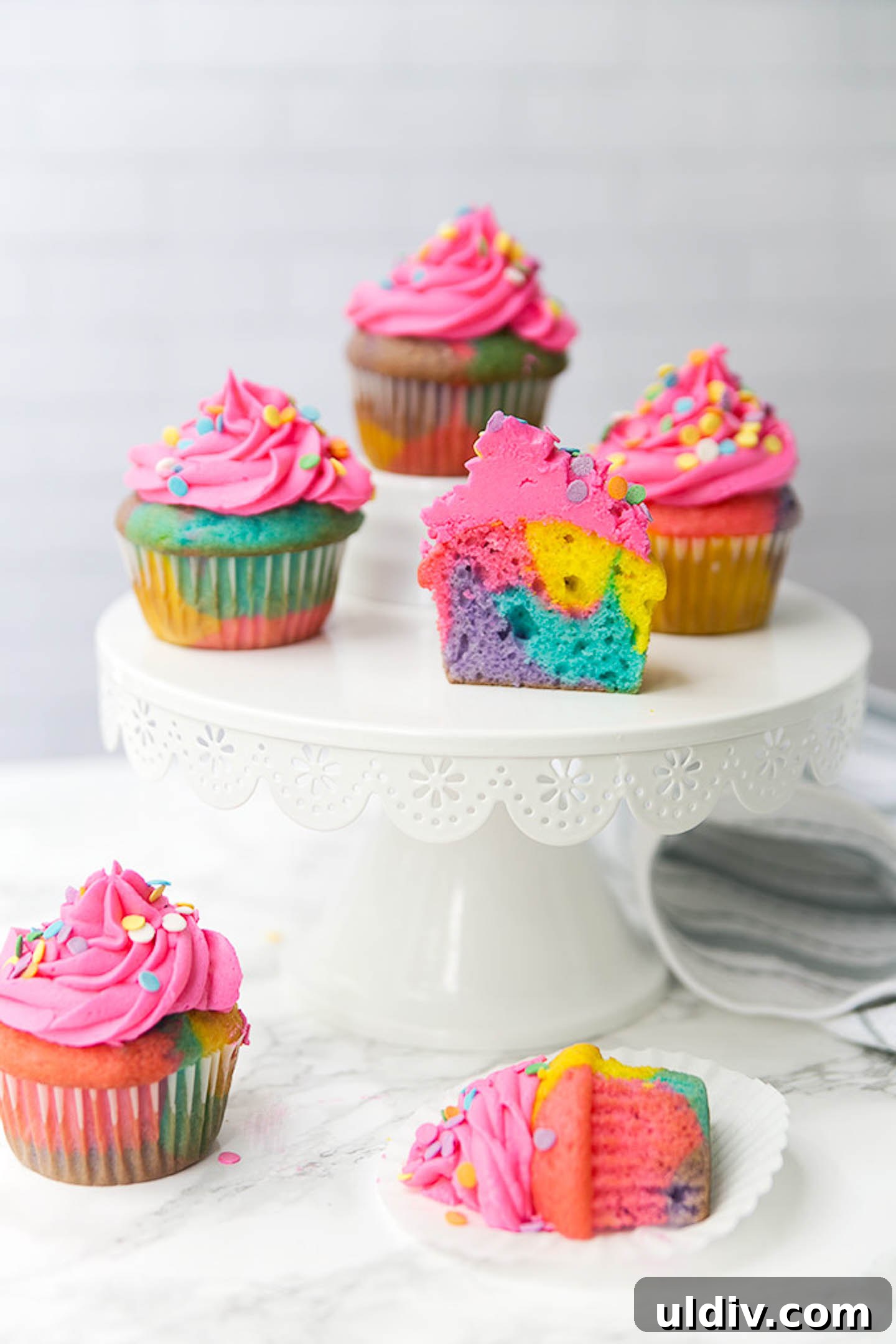 How to Make Colorful Rainbow Cupcakes: Step-by-Step Recipe 2 Rainbow marble cupcakes on a cakestand.
