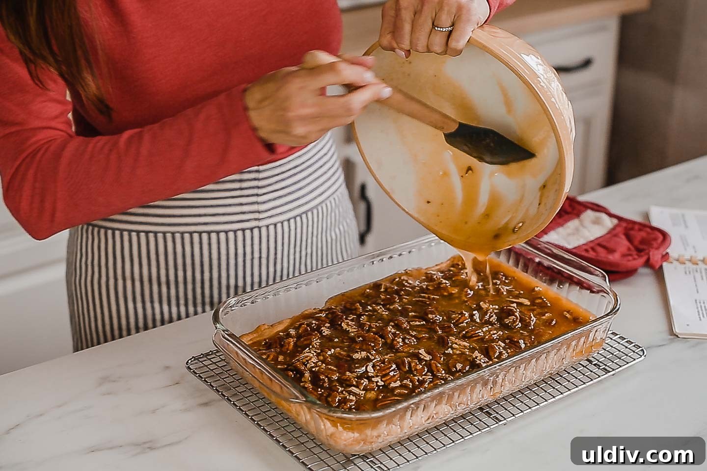 Chewy Pecan Pie Bars with Buttery Shortbread Crust 4 A woman pouring pecan pie filling over crust.