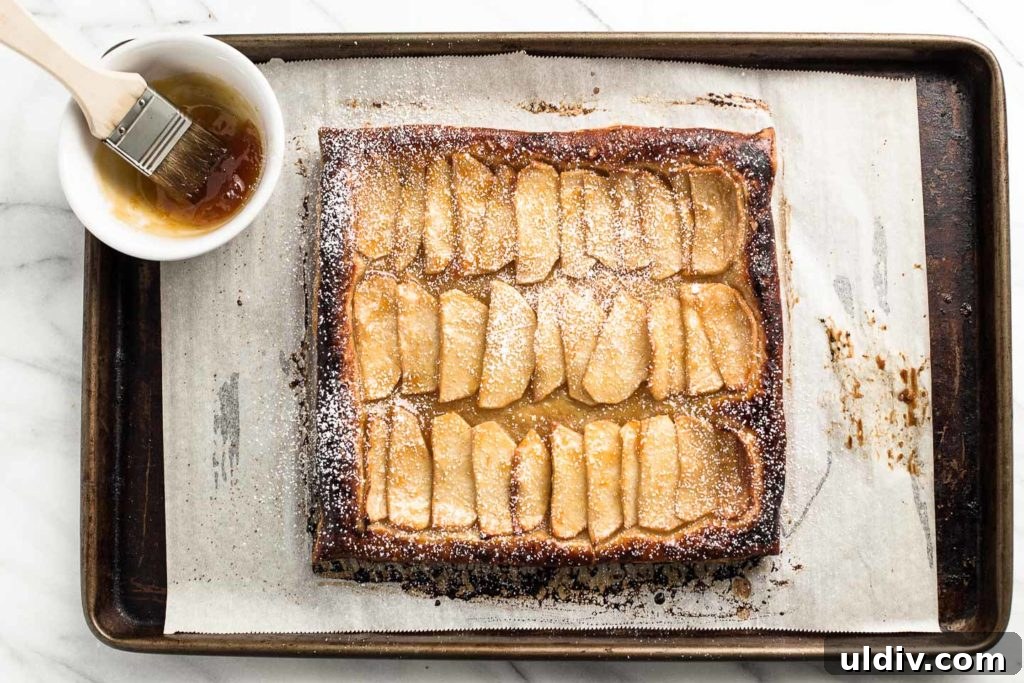 Rustic Apple Tart Recipe: Flaky, Cinnamon-Spiced Orchard Tart 3 apple tart on a baking sheet with apricot jam in a bowl.