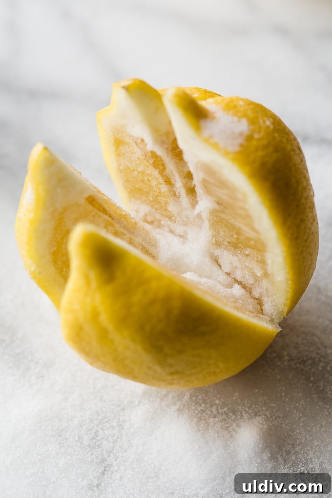 Homemade Preserved Lemons: Simple Step-by-Step Recipe 3 A lemon cut into quarters with salt on it.