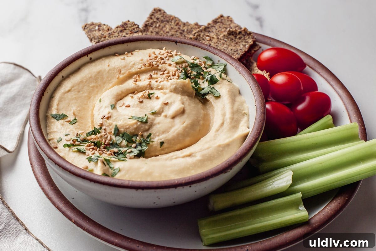 Oil-Free Hummus Recipe: Creamy Chickpea Dip Without Oil 4 Hummus in a bowl with a side of raw vegetables.