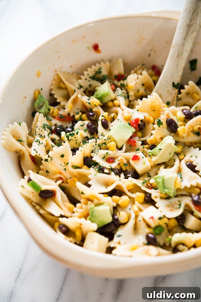 Southwest Pasta Salad embraces the sweetness of cream style corn, along with the spiciness of chipotle sauce that is perfect to serve on a hot summer day! Southwest Pasta Salad in a bowl on a counter top.