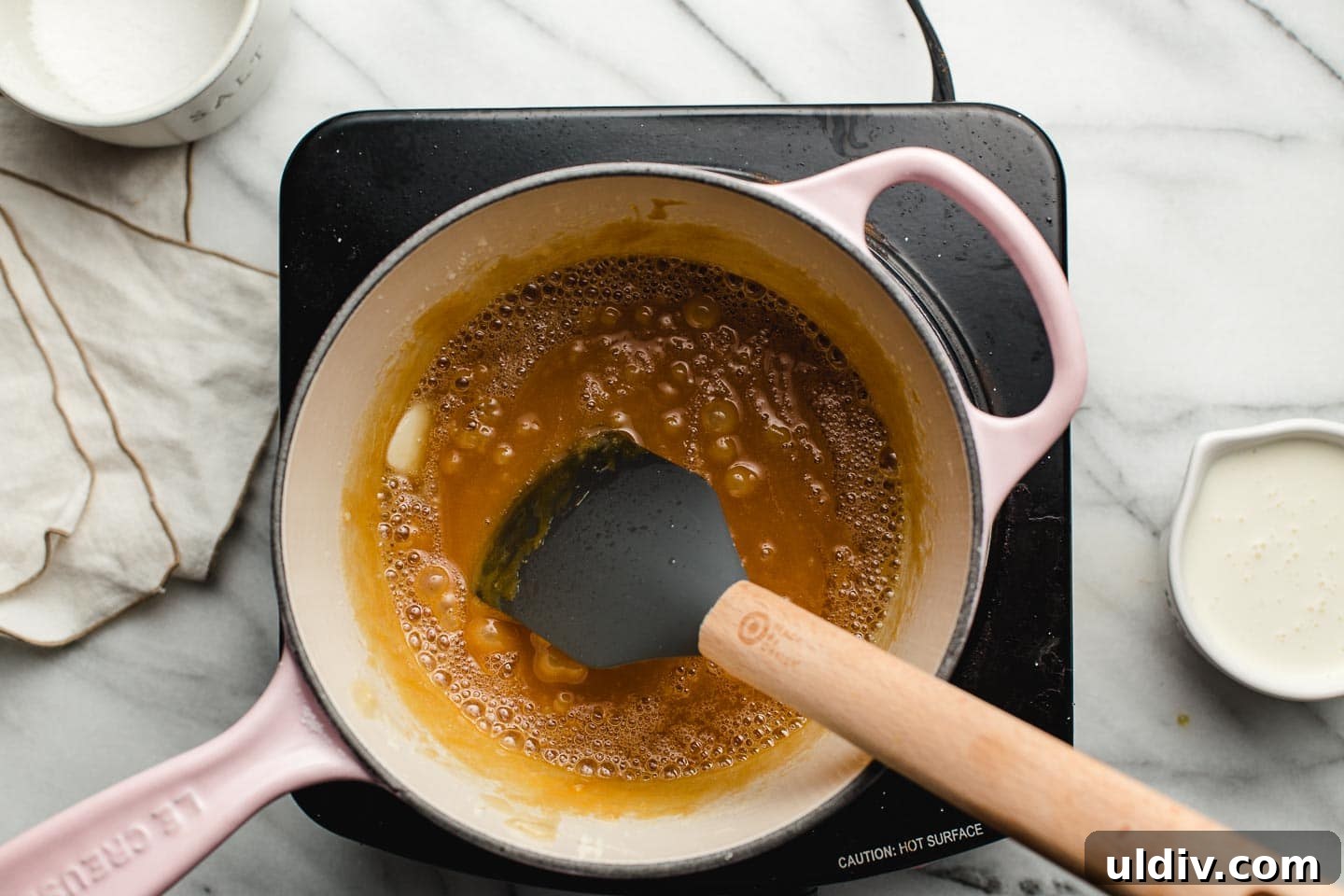 Homemade Salted Caramel Sauce Recipe for Smooth, Gooey Results 5 Adding butter to browned sugar in a saucepan.