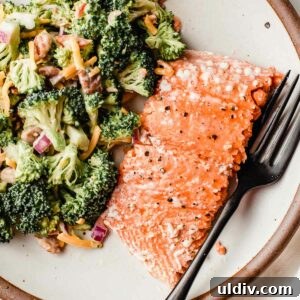 Oven-Baked Salmon with Lemon Herb Glaze 6 A piece of baked salmon on a plate with broccoli salad.