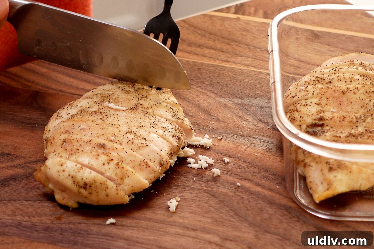 Juicy Oven-Baked Chicken Breasts with Garlic and Herbs 6 A woman slicing a chicken breast.