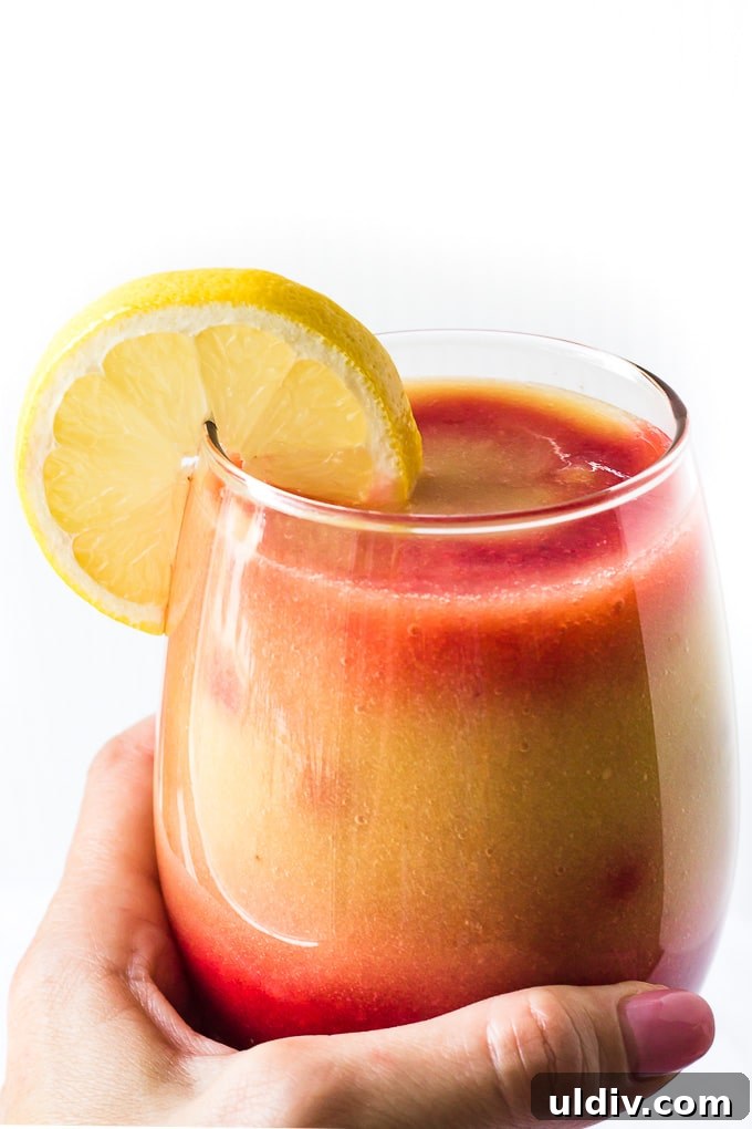 Sunrise Detox Smoothie is a light and refreshing way to start your day! A hand holding a glass of a sunrise detox smoothie.